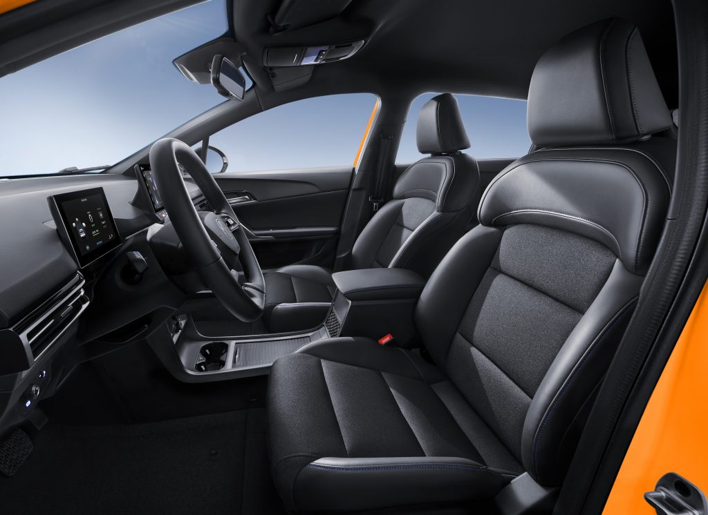 Innenraum des MG4 Electric mit Fokus auf die Vordersitze, das Lenkrad und das Infotainment-Display. Schwarz-blaue Sportsitze.