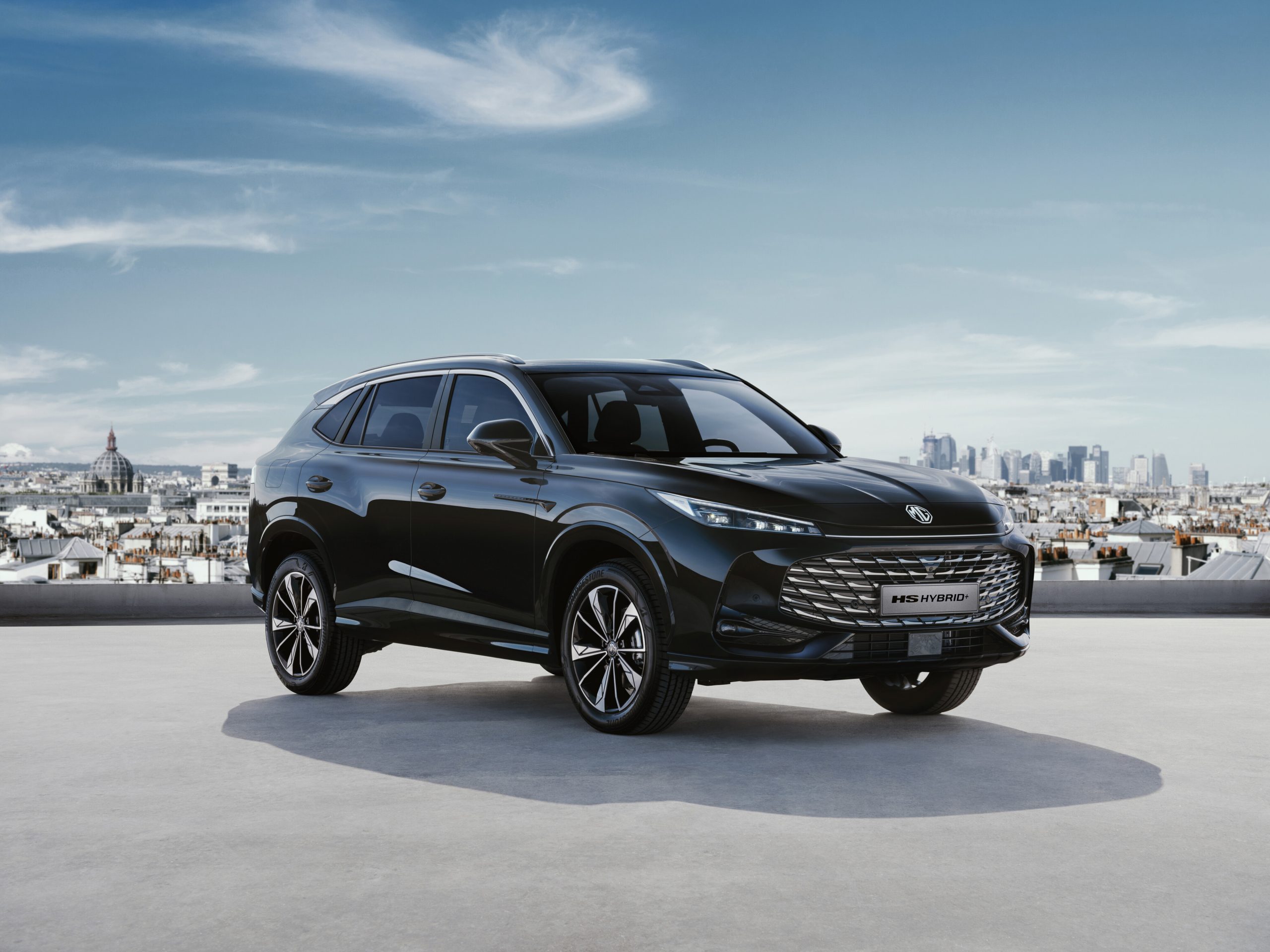 MG HS Hybrid plus schwarz Ansicht vorne rechts schräg Hintergrund Stadt