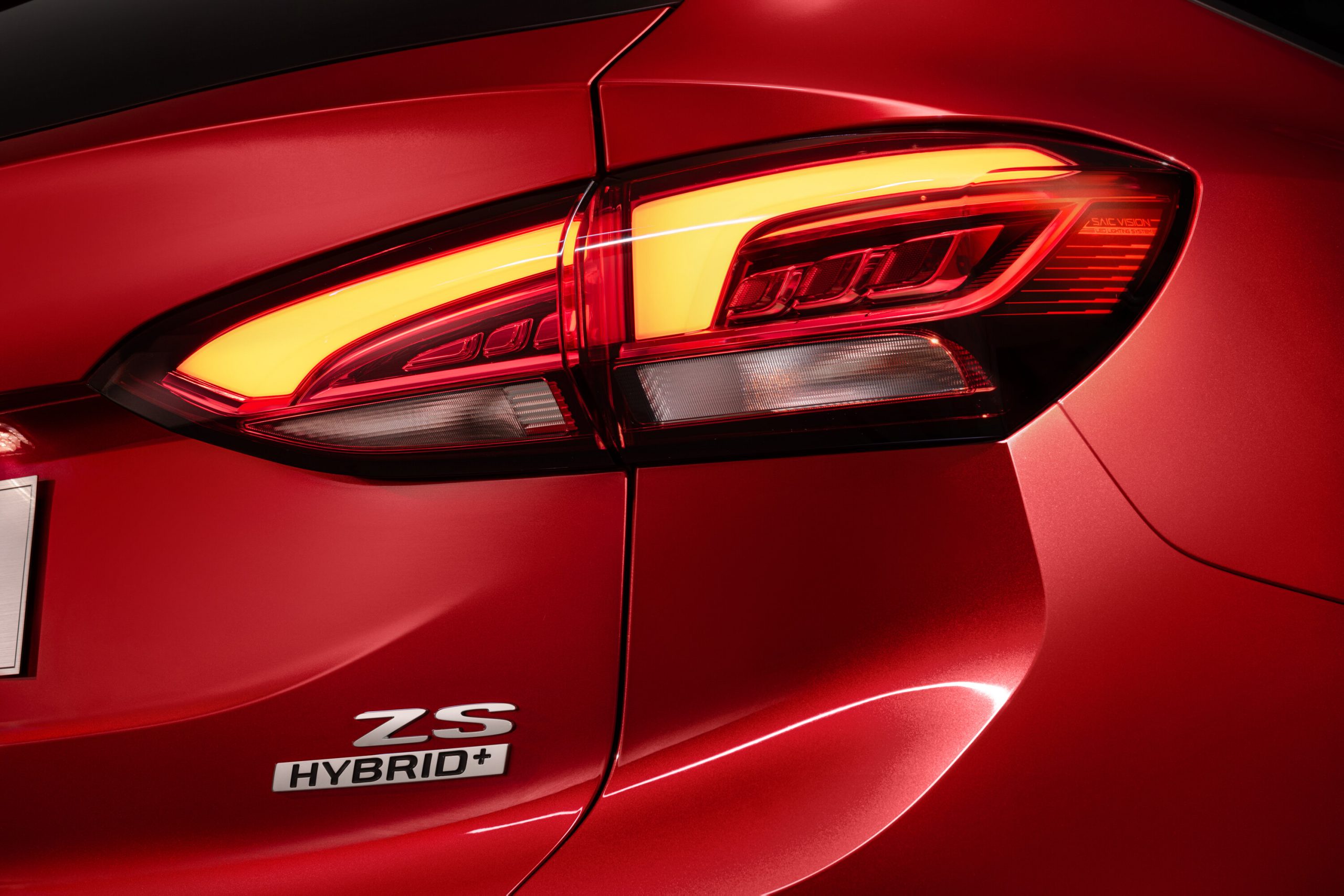 Rote Heckansicht eines MG ZS Hybrid+ Crossovers mit beleuchteter LED-Rückleuchte und "ZS HYBRID+" Emblem.